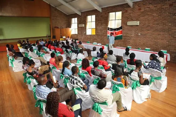 Children and families in a hall decorated with Kenyan flags